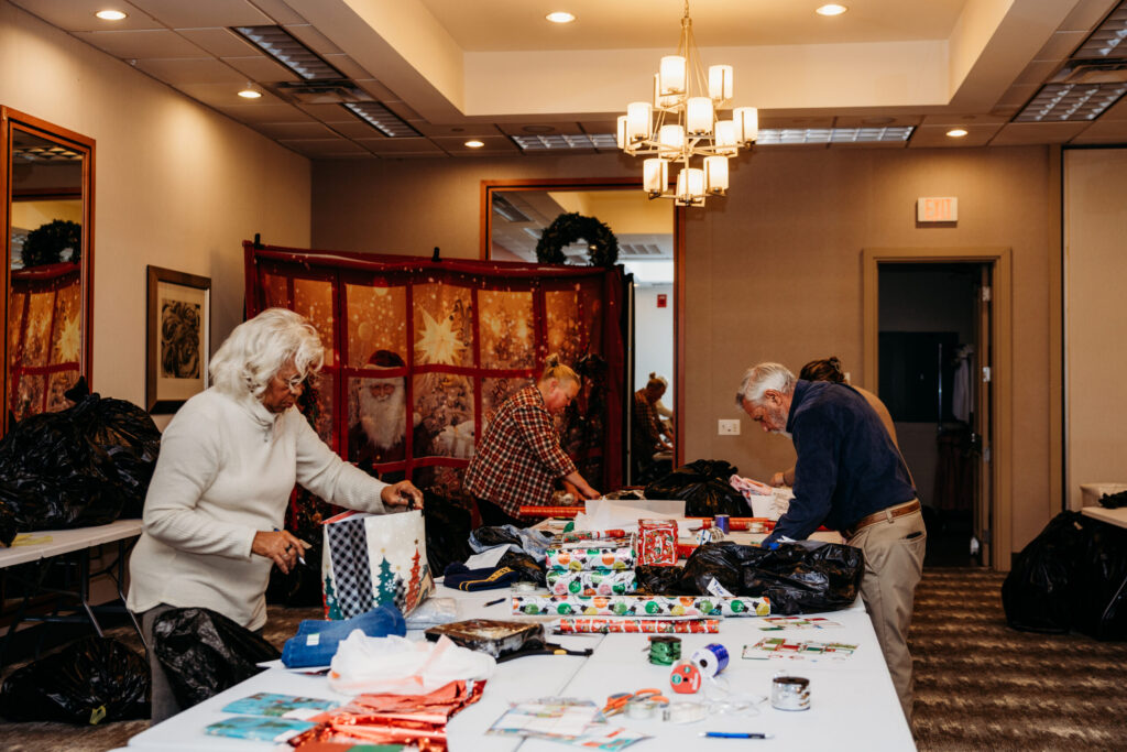 A small group of people participate in a craft or art workshop around a table in an elegantly decorated indoor venue with warm lighting and wooden furnishings.