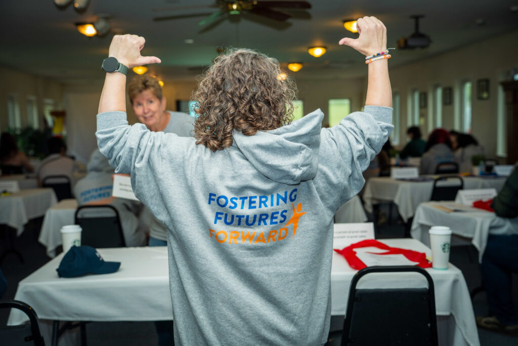 A fitness instructor celebrates with raised dumbbells during a group workout class in an indoor gym facility.