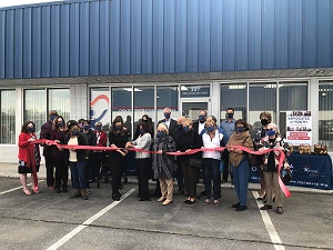 People standing in front of building holding ribbon